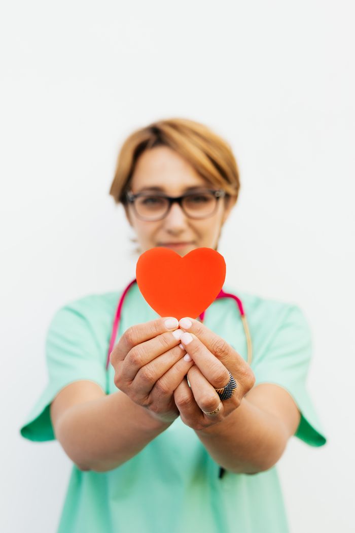 Focused healthcare worker holding a red heart, symbolizing care and compassion.
