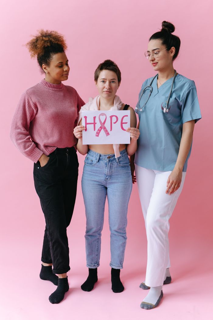 Diverse group of women promoting breast cancer awareness with a 'Hope' sign.